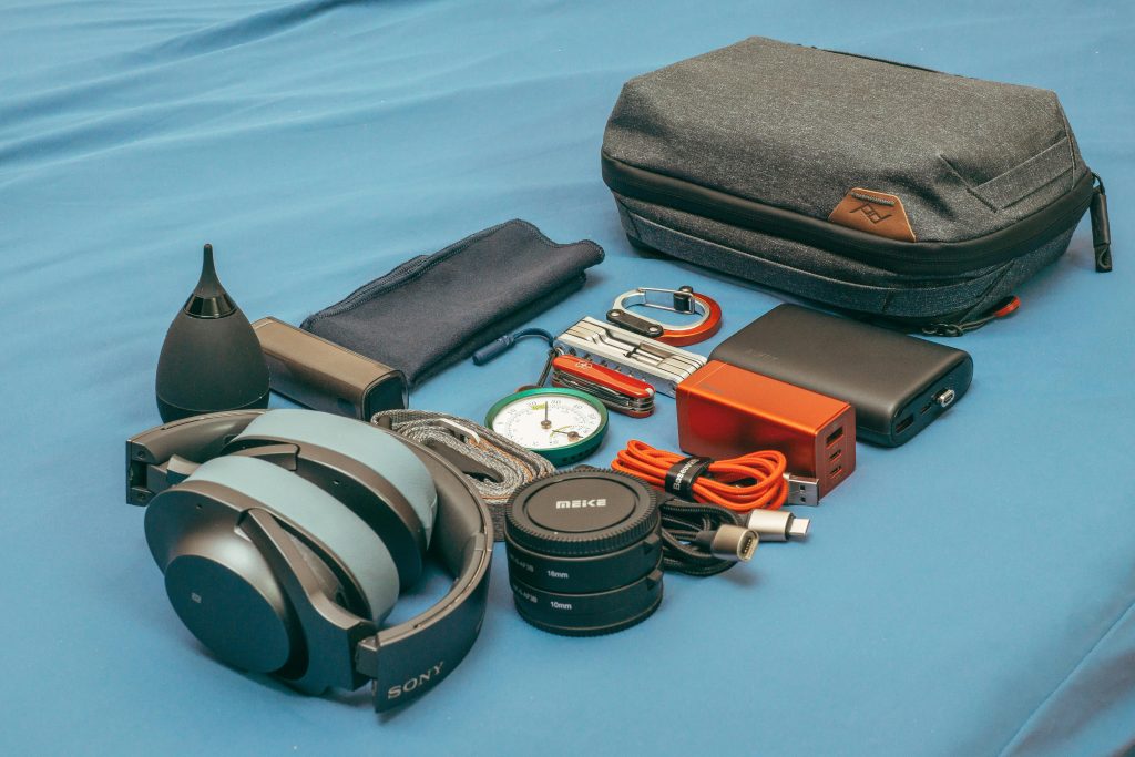 Flat lay of travel electronics including phone, headphones, and power bank